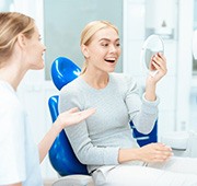 a patient checking her brightened smile with a mirror